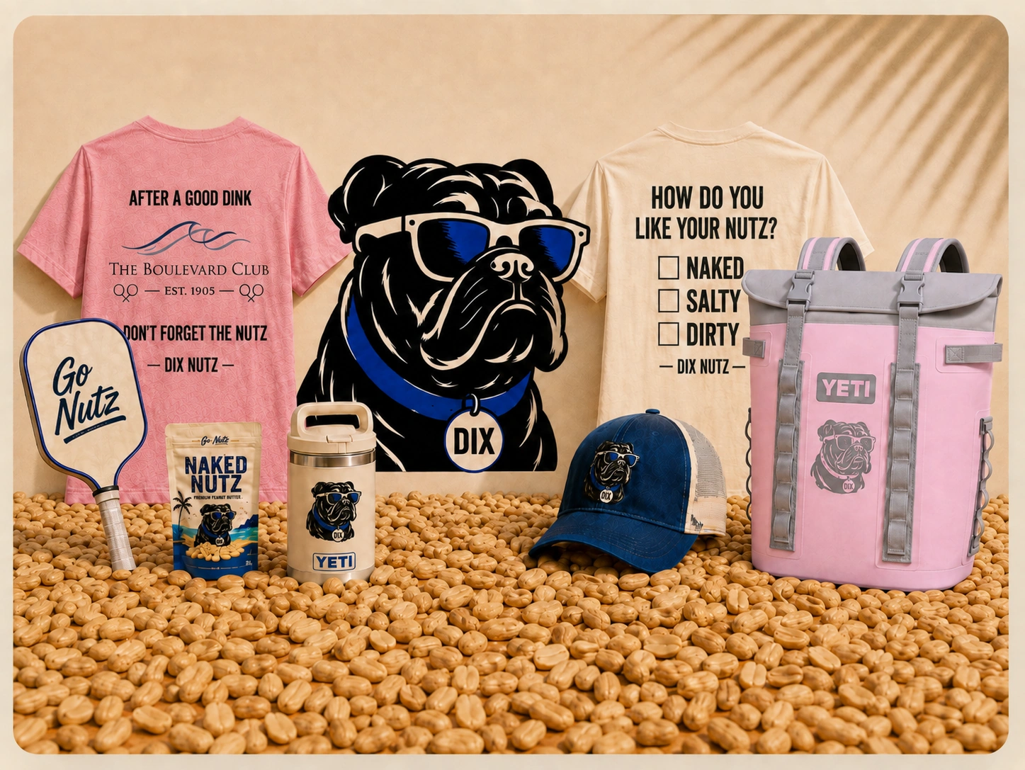 Dix the bulldog with Dix Nutz branded merchandise including shirts, drinkware, hat, pickleball paddle, and the pink YETI cooler backpack on a bed of shelled peanuts.